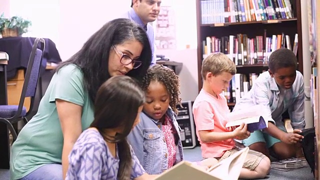 教师、图书管理员在图书馆或教室里为小学生读书。视频素材