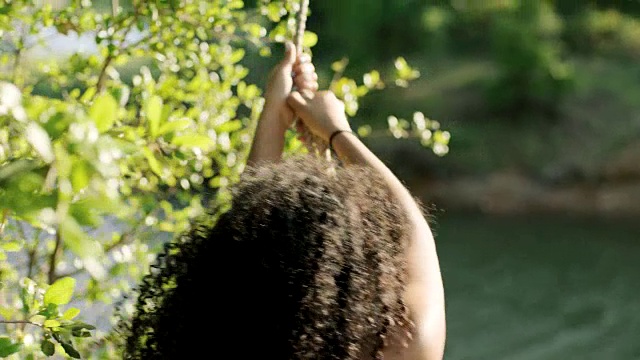 一名少女带着秋千从河岸上跳下，坠入水中，溅起了巨大的水花。视频素材