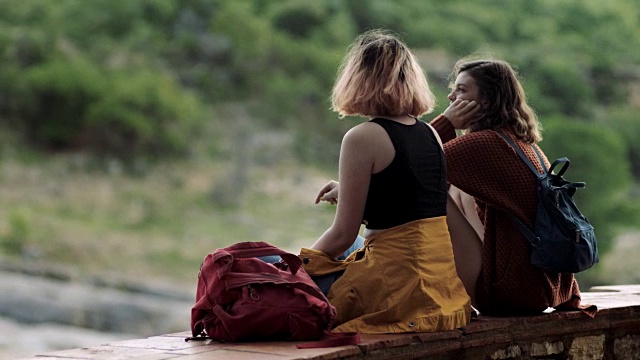 两个女孩谈笑风生，在风景秀丽的国家公园的山上俯瞰。视频素材