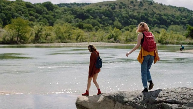 在风景秀丽的州立公园里，两个女孩徒步穿越岩石来到河边。视频素材