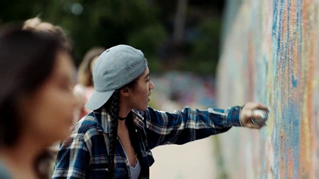 在德克萨斯州奥斯汀的贝勒街艺术墙上，女孩们在喷漆涂鸦。视频下载