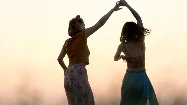 在神奇的时刻，女孩们穿着飘飘的裙子在夏日的麦田里跳舞。视频素材