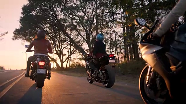 三个女性朋友在摩托车上一起笑在日落驾驶。视频素材