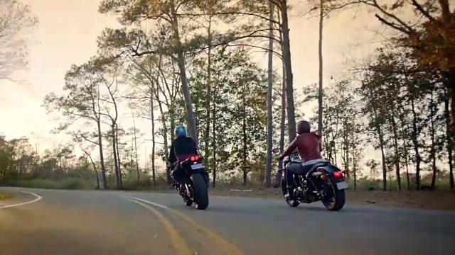 日落时分，两名女子骑着摩托车在沿海公路上行驶。视频素材
