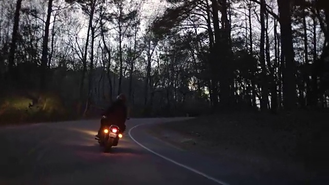 SLO MO:一对夫妇骑着摩托车在晚上穿过州立公园森林。视频素材