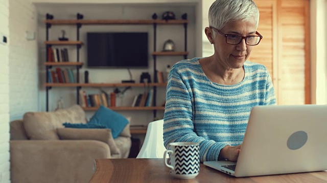 一个在家里用笔记本电脑打字的成熟女人。视频素材