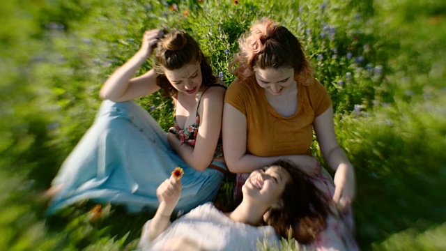 三个女孩一起在花丛中欢笑。视频素材