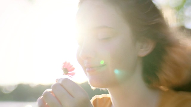 女孩在阳光明媚的日子里闻到野花的味道。视频素材