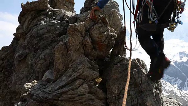 一名男性登山运动员攀登雪山之上的岩石山脊视频素材