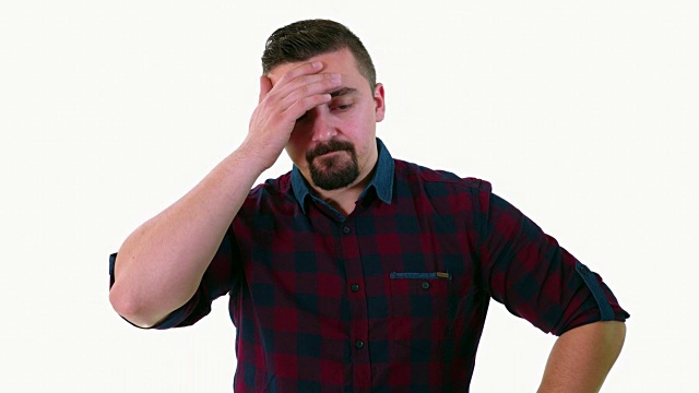 一名成年男子站在一个白色的摄影棚背景前，带着担忧或悲伤的表情看着摄像机视频素材