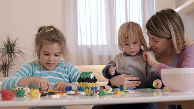 小孩子和他们的妈妈在家里玩拼图。视频素材