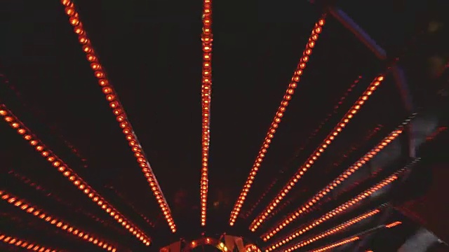 英国埃塞克斯，从一辆华尔兹车拍摄的视频，显示了在游乐场上旋转的汽车被照亮的车顶。视频素材