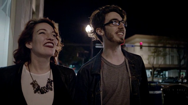 MS SLO MO.年轻的夫妇指着建筑物在夜晚探索城市。视频素材