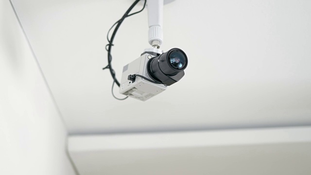 一个安装在白色天花板上的安全摄像头的旋转镜头视频素材