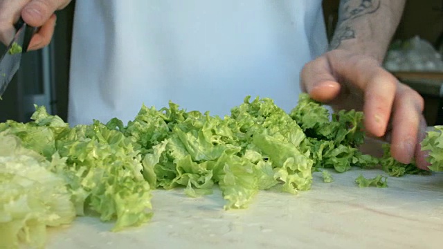 厨师们亲手切一片新鲜的绿色沙拉叶子。视频下载