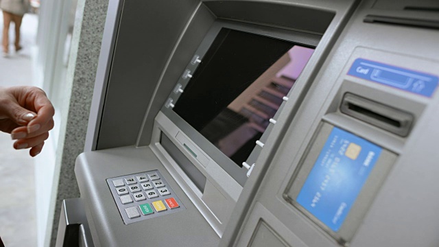 女性手将银行卡插入ATM插槽，输入密码，从显示菜单中进行选择视频素材