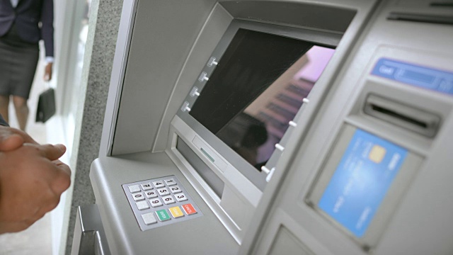 身份证持有人将银行卡插入自动柜员机插槽，并输入个人密码进行取款视频素材