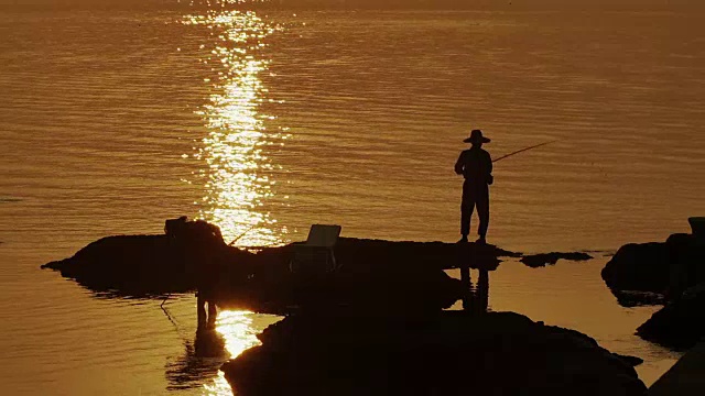 日落时分，人们在岩石上钓鱼视频下载