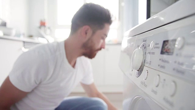一名年轻人正在往洗衣机里加衣服视频下载