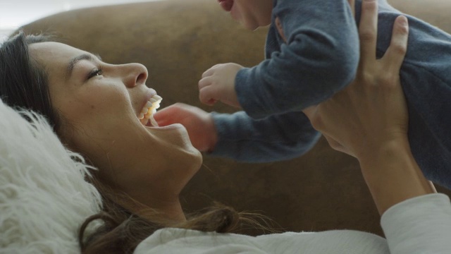 近距离的母亲躺在沙发上举起婴儿的儿子/普罗沃，犹他州，美国视频素材