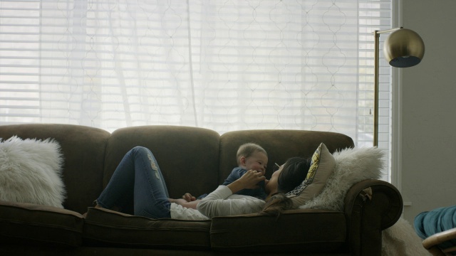 美国犹他州普罗沃，一名妇女躺在沙发上和婴儿玩耍的中镜头视频素材