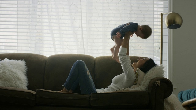 美国犹他州普罗沃，一名妇女躺在沙发上抱着自己的儿子视频素材