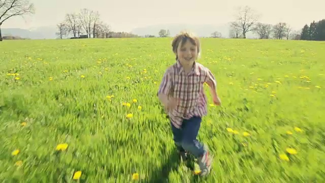 一个小男孩在绿色的草地上奔跑视频素材