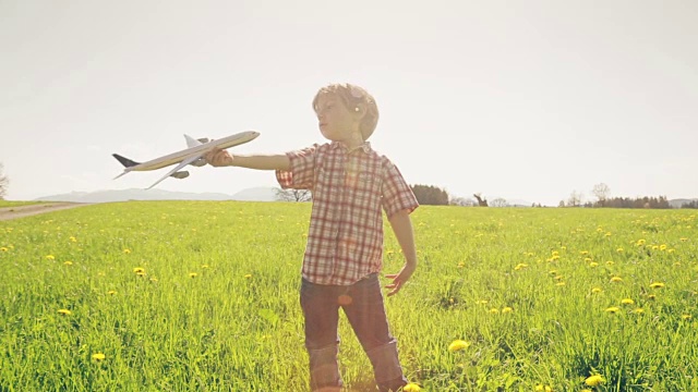 一个小男孩在草地上玩飞机视频素材