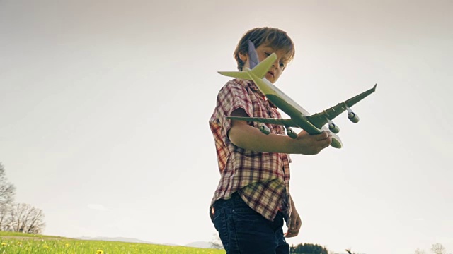 一个小男孩在草地上玩飞机视频素材