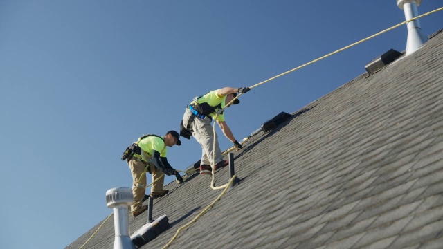 宽平移低角度拍摄的工人在屋顶检查安全线/梅普尔顿，犹他州，美国视频素材