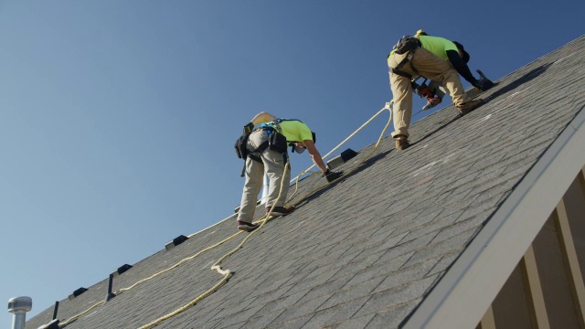 宽平移低角度拍摄工人在屋顶上钻孔/ Mapleton，犹他州，美国视频素材