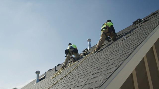 宽平移低角度拍摄的工人安装在屋顶上的部件/ Mapleton，犹他州，美国视频素材