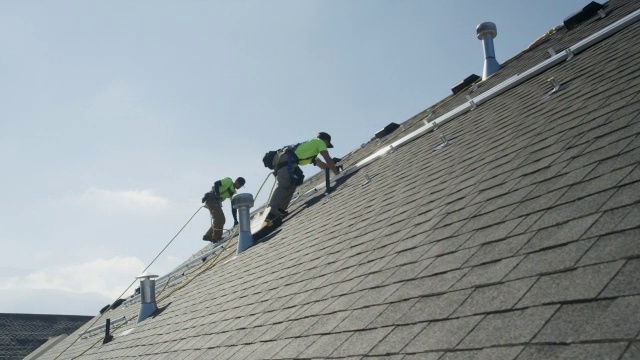 宽平移低角度拍摄的工人在屋顶上安装铁轨/ Mapleton，犹他州，美国视频素材