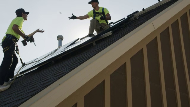 中等平移低角度拍摄工人在屋顶安装太阳能电池板/ Mapleton，犹他州，美国视频素材