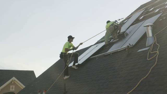 工人在屋顶安装太阳能电池板的宽平移低角度拍摄/美国犹他州梅普尔顿视频素材