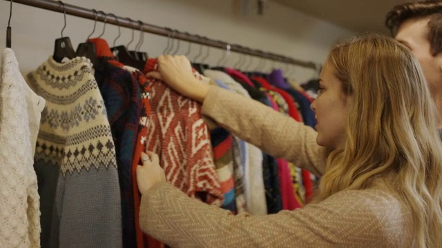中等镜头的男人看着女人购买复古毛衣/普罗沃，犹他州，美国视频下载