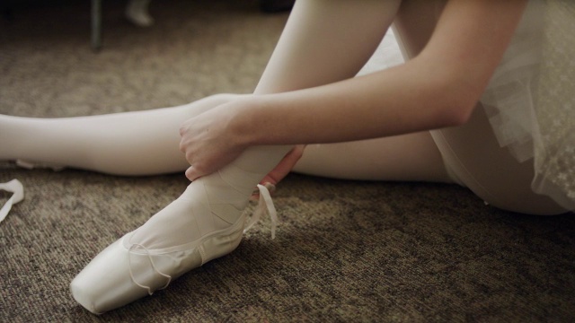 芭蕾舞女演员坐在地板上穿芭蕾舞鞋的特写/盐湖城，犹他州，美国视频下载