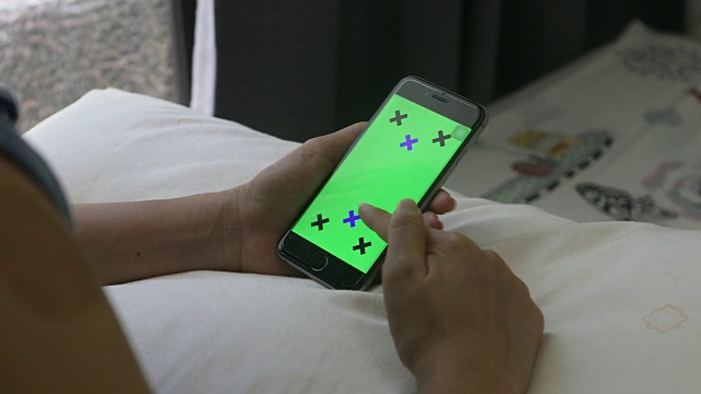 女人的手握着智能手机的绿色屏幕的特写，预设的效果视频素材