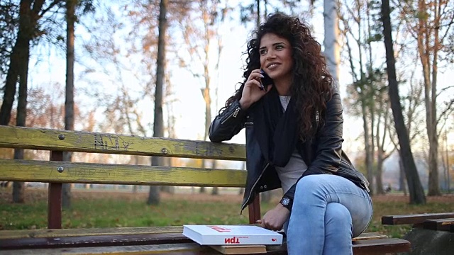 漂亮女孩坐在公园里愉快的电话对话视频下载