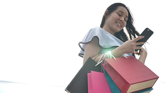 亚洲女人用购物袋在智能手机上购物视频素材