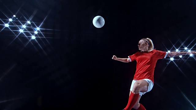 SLO MO LD女子足球运动员在黑色背景的空中踢球视频素材