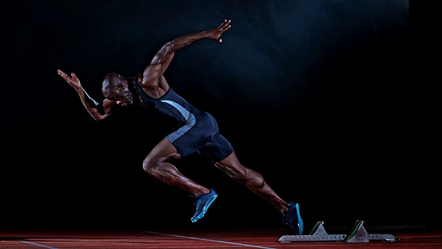 SLO MO TS一名非裔美国男子短跑运动员从起跑台出发的侧面镜头视频素材