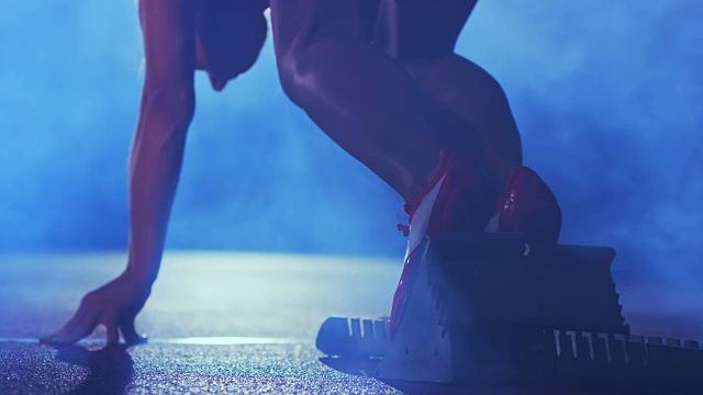 SLO MO女子白种短跑运动员在一个黑色的朦胧背景上从起跑线上起飞视频素材