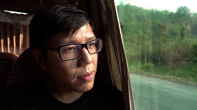戴眼镜的亚洲人从巴士上看视频下载