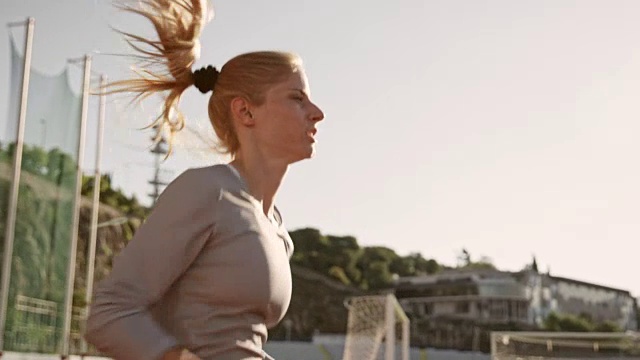 SLO MO女人在阳光下的体育场跑步视频素材