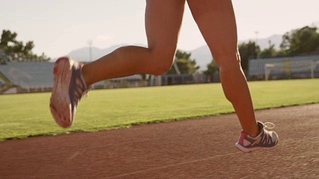一个长马尾的白人妇女在阳光明媚的体育场内奔跑视频素材