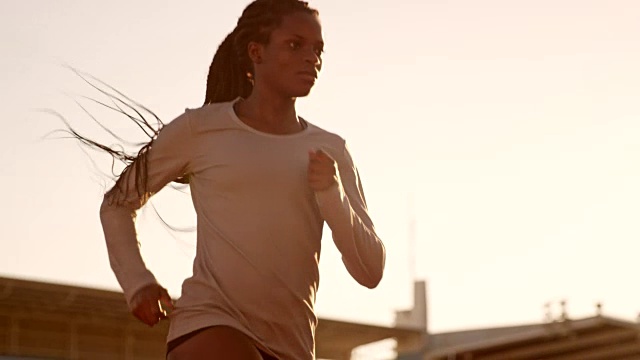 SLO MO DS非裔美国妇女在日落时在体育场跑步视频素材