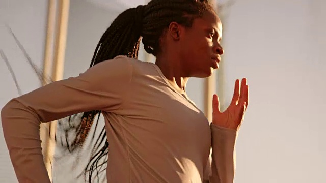 梳着辫子的非裔美国女运动员在日落时在体育场奔跑视频素材