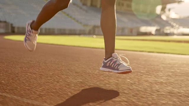 一个非裔美国妇女在日落时在体育场跑步的腿视频素材