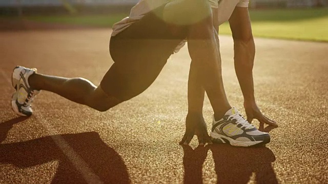 夕阳下，一名非裔美国人的双腿在体育场的跑道上伸展视频下载